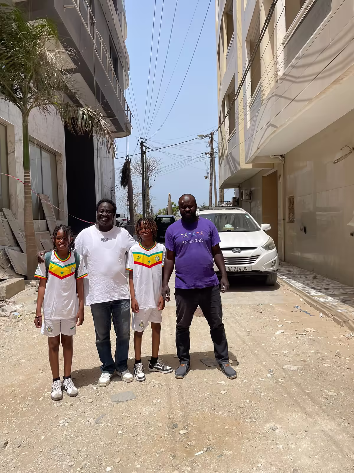 Diambar et de jeunes voyageurs en maillot du Sénégal dans une rue de Dakar