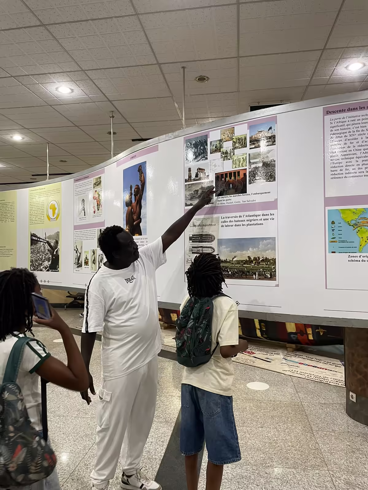 Guide expliquant les panneaux de l'exposition sur la traite atlantique à de jeunes visiteurs