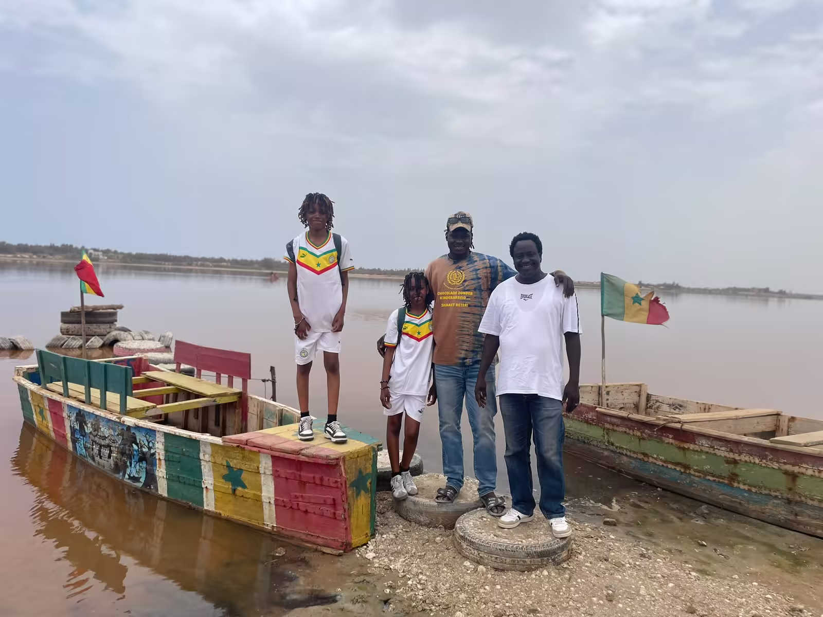Famille de voyageurs devant les pirogues aux couleurs du Sénégal au Lac Rose