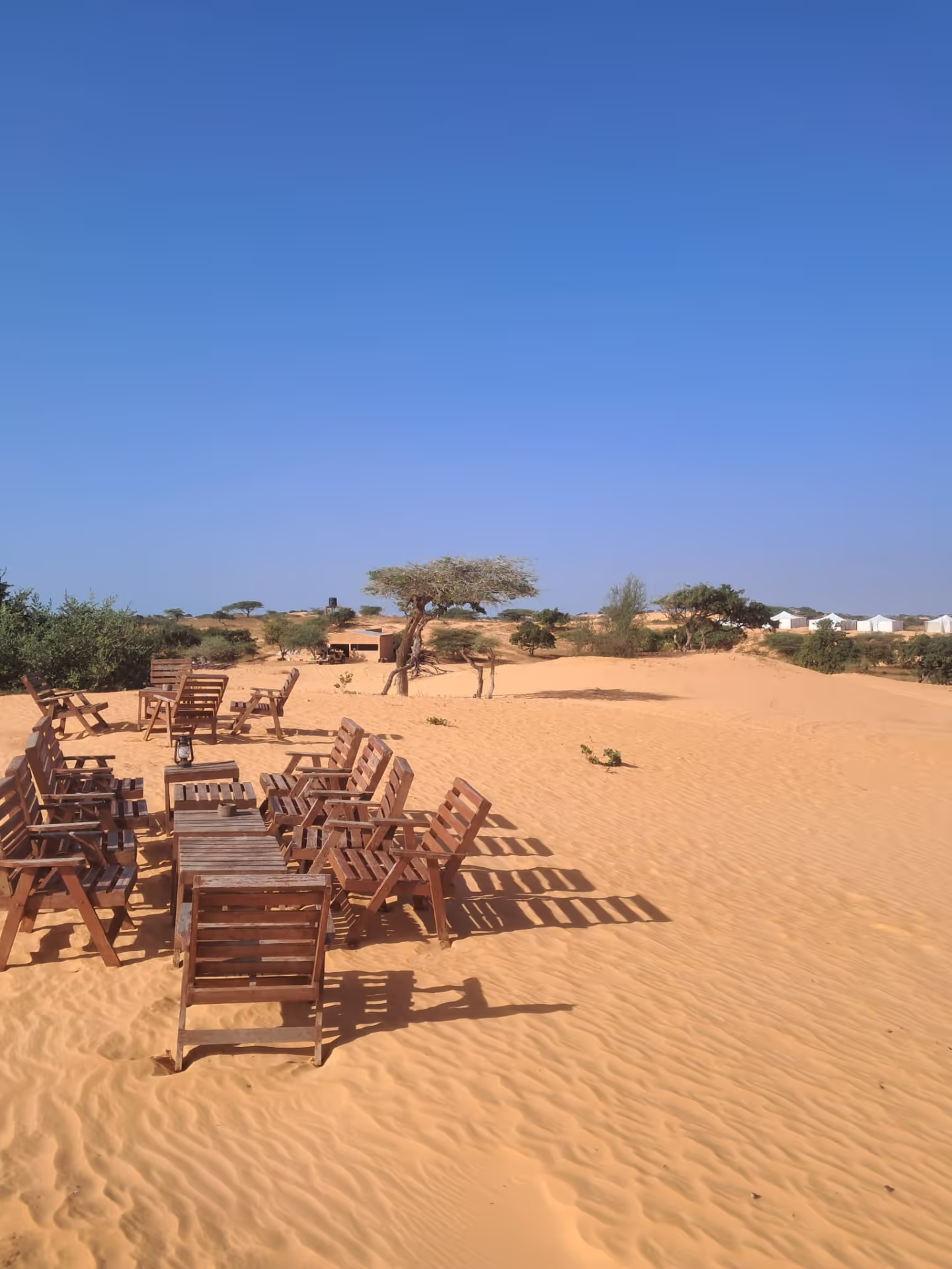 Désert de Lompoul, chaises en bois sur le sable devant les tentes du campement