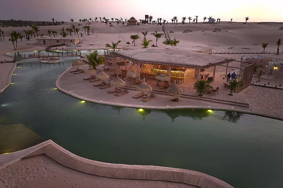 Lodge au bord d'une piscine au coucher du soleil dans le désert de Lompoul